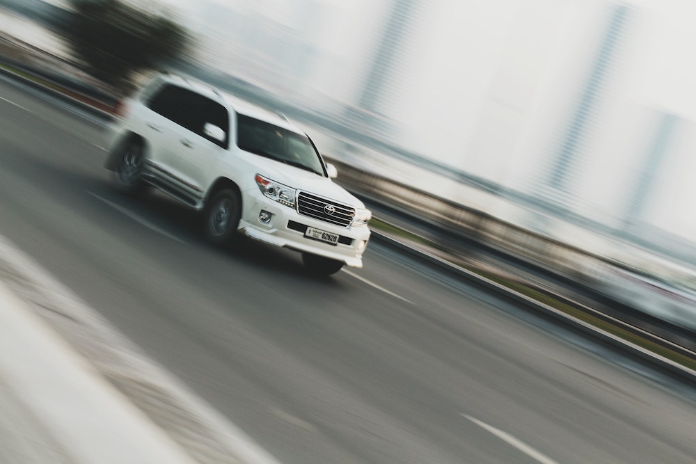 White Toyota SUV driving on a road.