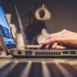 A close up side shot of a person working on a laptop.