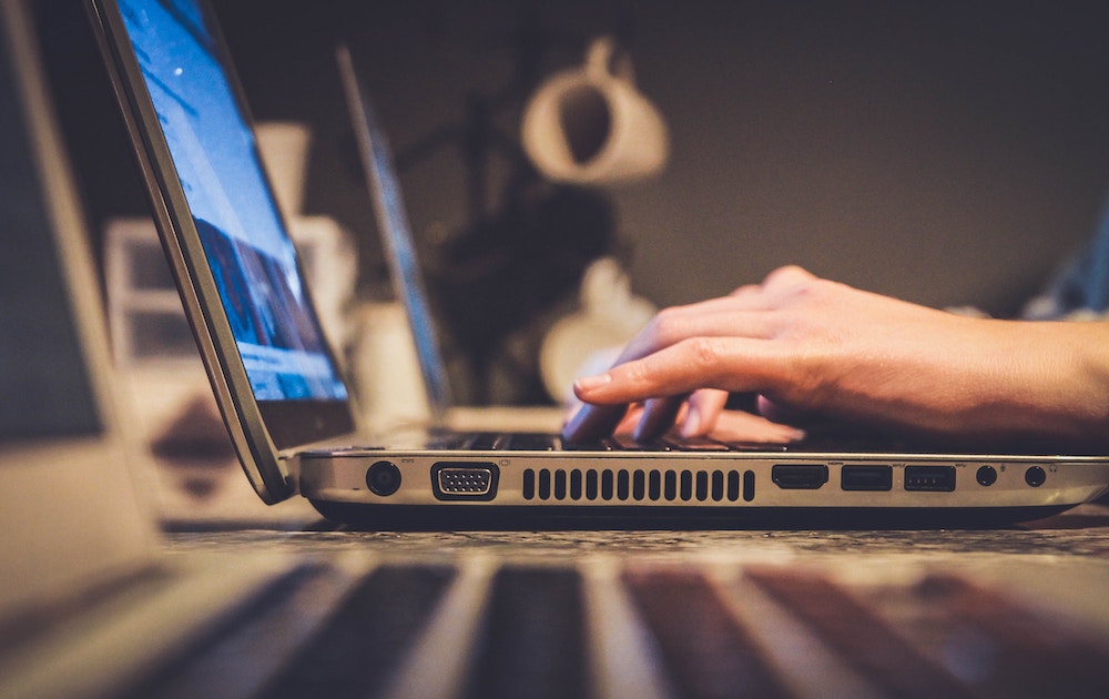 A close up side shot of a person working on a laptop.
